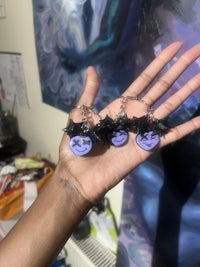 a person's hand holding a set of purple and black charms